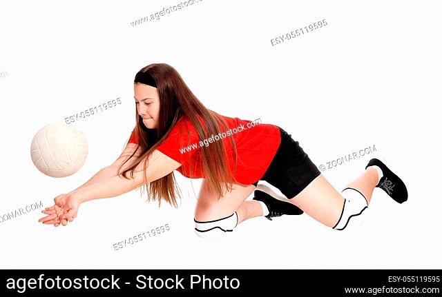A teenage girl playing volley ball in her uniform on her knees try to catch the ball, isolated for white background