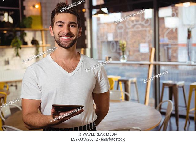 Portrait of waiter holding tablet in cafe