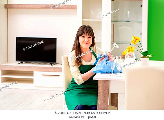 Young woman cleaning glasses at home