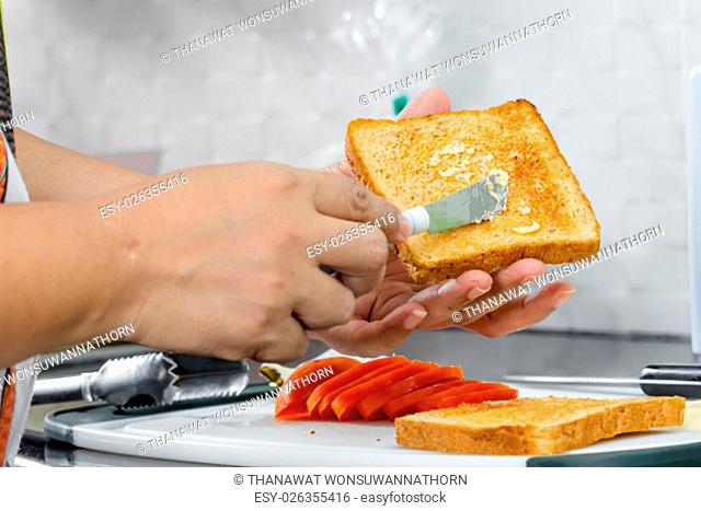 women hand spreading butter on toast