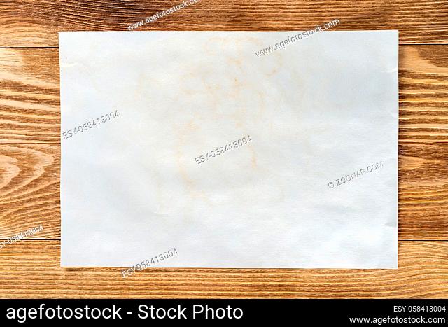Flat lay wooden table with paper sheet. Blank white a4 format paper. Space for writing and notification. Textured natural wooden background for message