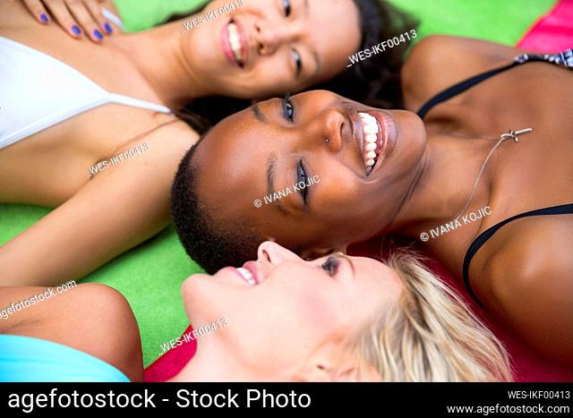 Smiling friends lying on colorful blanket