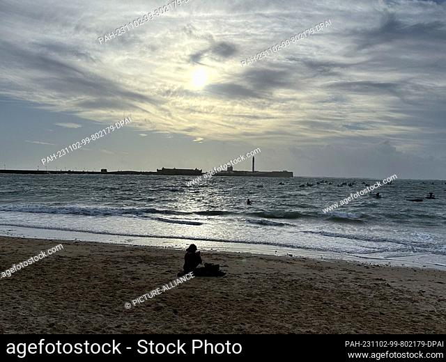 02 November 2023, Spain, Cádiz: A woman sits on La Caleta beach in Cadiz. Photo: Benedikt von Imhoff/dpa. - Cádiz/Andalusia/Spain