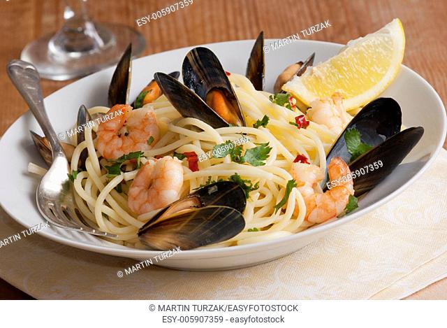 Spaghetti with king prawns, mussels and herbs on a plate