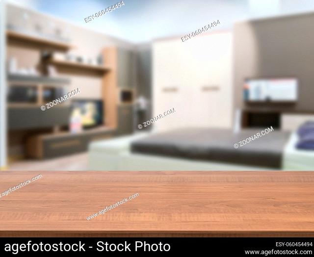 Wooden board empty table in front of blurred background. Perspective dark wood over blur in modern comfortable bedroom with white bed