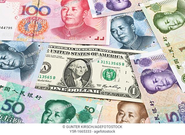 Many Yuan bills with the portrait of Mao Zedong lying side by side In the middle lies a 1 U S Dollar bill The renminbi, the Chinese currency
