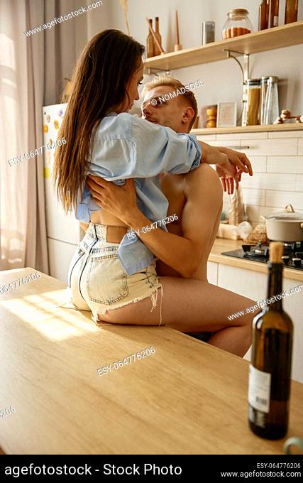 Romantic couple kissing on home kitchen view from back. Seductive loving man and woman enjoying intimate time together