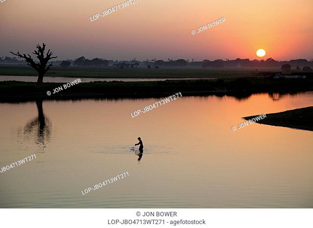 Myanmar, Mandalay, Lake Taungthaman. A fisherman on Taungthaman Lake in Myanmar at sunset viewed from U Bein Teak Bridge