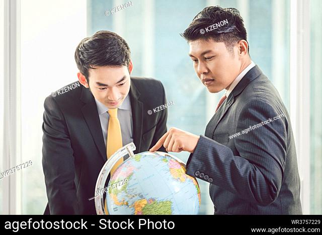 Close-up of two young businessmen looking at globe