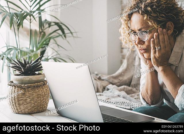 People and problems with computer concept. Woman looking laptop display with worried expression on face. Adult female read bad notification on notebook at home
