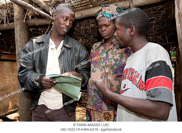 Aid worker talking to family baout milk yield records of cow. Rwanda. (Photo by: Wayne Hutchinson/Farm Images/UIG)
