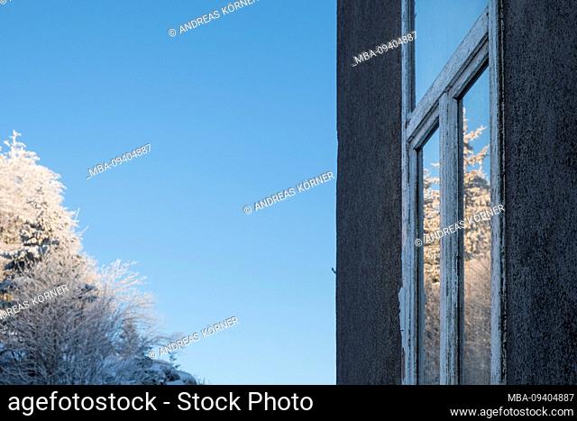 House facade with window and reflection of a sunny, wintry landscape in the Vosges, France