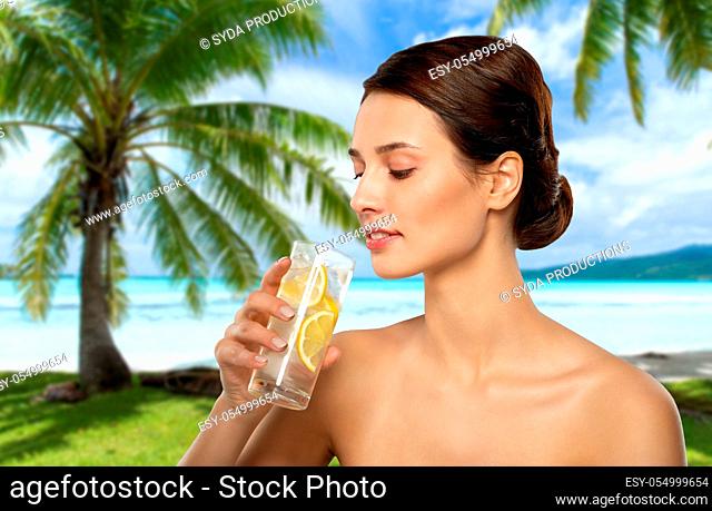 woman drinking ice water with lemon over beach