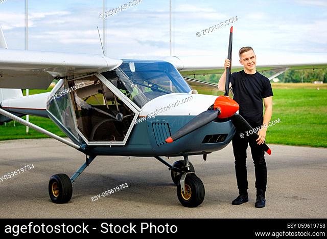 handsome teenage man standing near small private plane. young pilot. outdoor shot