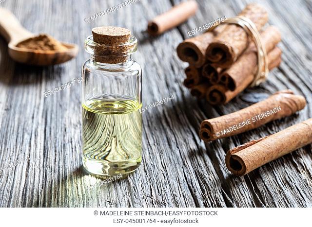 A bottle of essential oil with cinnamon sticks and powder