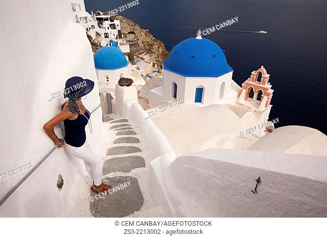 Woman in front of a blue domed church in Oia town with a ferry at the background, Santorini, Cyclades Islands, Greek Islands, Greece, Europe