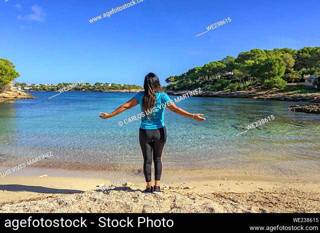 latina woman, in sportswear on her back, on the shore of the beach looking at the sea breathing deeply. ,
