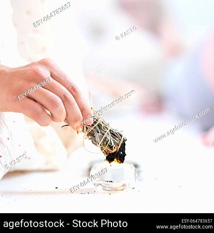 Woman lighting a smudge kit with herbal stick. Natural elements for cleansing environment from negative energy, adding positive vibes