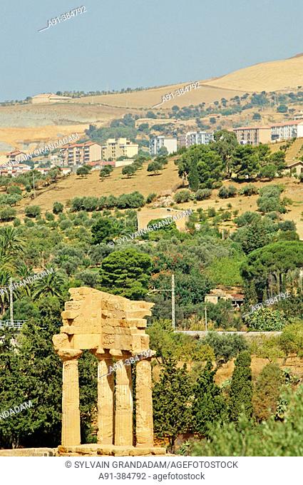 View on the city from The Valley of Temples, ruins of Castor and Pollux temple at fore . Agrigente. Sicily. Italy