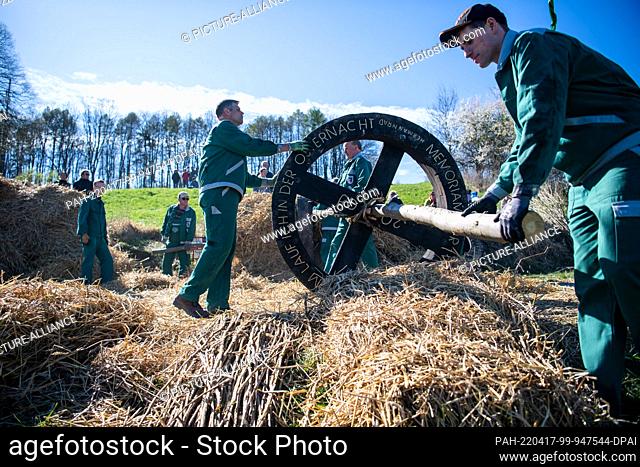 17 April 2022, Lower Saxony, Lügde: An Easter wheel is rolled by members of the Dechenverein for stuffing. When it is dark the straw in the wheels is lit and...