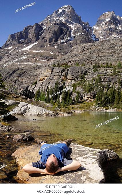 Hiker relaxing on a rock, Lake O'Hara, Yoho National Park, British Columbia, Canada