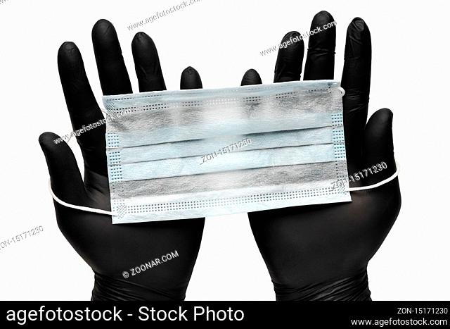 Doctor holds surgical face mask in hands in black medical gloves. Isolated on white background. Pandemic insurance, airborne diseases, SARS, influenza