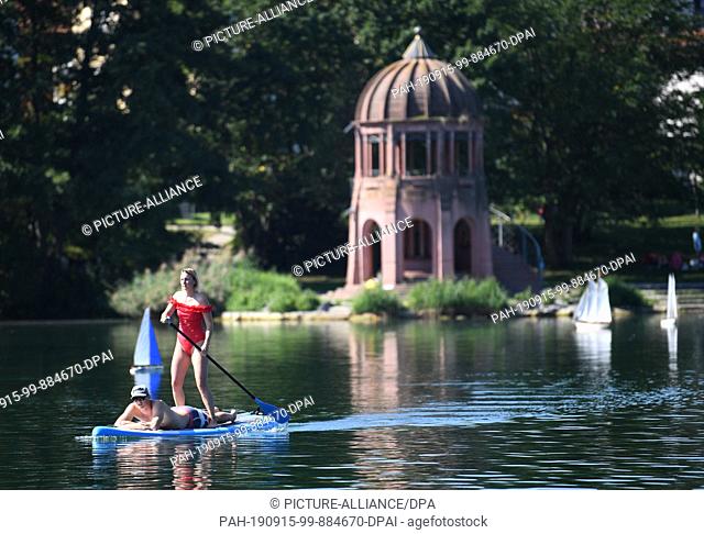 15 September 2019, Baden-Wuerttemberg, Freiburg: Sonja and John enjoy the warm temperatures on a stand up paddling board on Lake Flückigersee