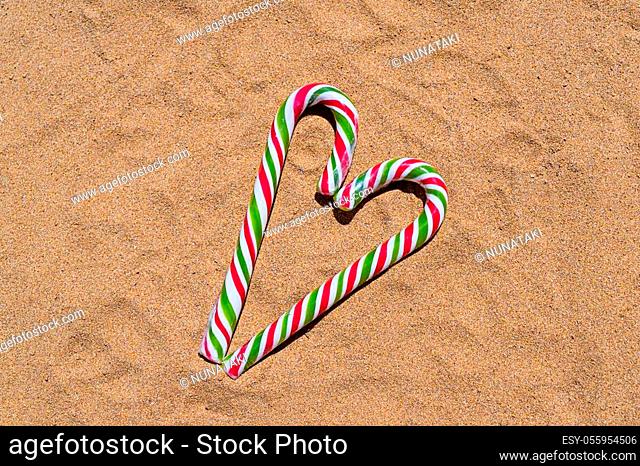 Christmas candy cane heart on sandy beach with copy space. Merry Christmas and Happy New Year at beach concept