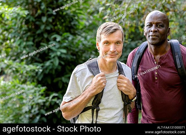 Two male friends hiking in the woods stop to take a picture