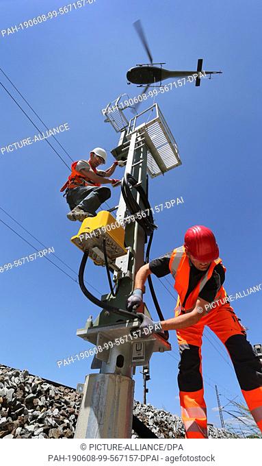 08 June 2019, Bavaria, Meitingen: Employees of a specialist company screw a railway signal pole, which had previously been brought by a helicopter