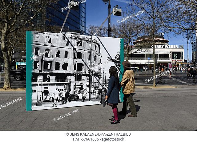 Pedestrians look at a partition wall with a historic picture of Joachimsthaler Platz (Joachimsthal Square) from May 1945 that has been placed at the same...