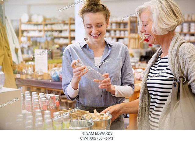 Mother and daughter shopping, browsing glass bottles in shop