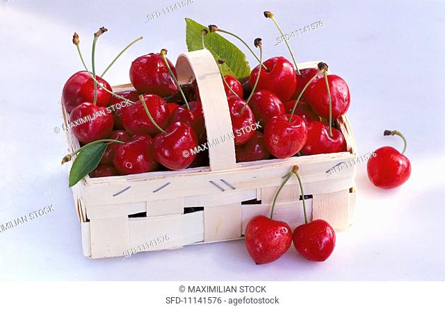 A wooden basket of sweet cherries