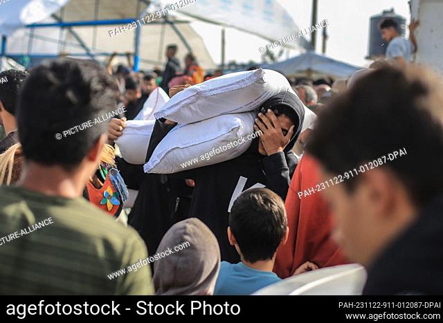 22 November 2023, Palestinian Territories, Khan Yunis: Palestinians receive bags of flour at the United Nations Relief and Works Agency for Palestinian Refugees...