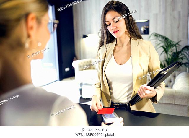 Businesswoman paying with contactless credit card at reception