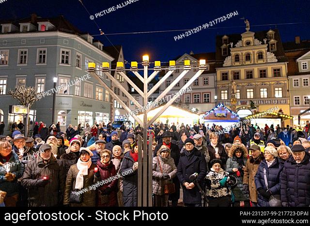 07 December 2023, Thuringia, Erfurt: People celebrate the lighting of the first light at the Hanukkah candelabra in front of the town hall