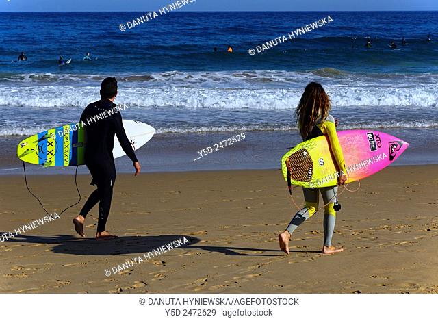 Europe, Portugal, Southern Portugal , Algarve , Faro district , Sagres, Mareta beach - Praia da Mareta, young surfes entering waters of Atlantic Ocean