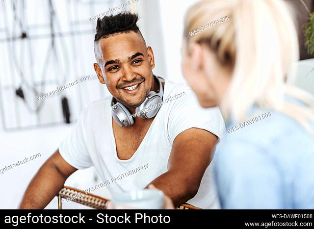 Portrait of smiling man with headphones listening to a friend