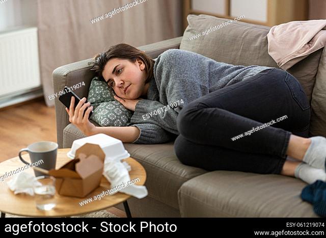 stressed woman with smartphone on sofa at home