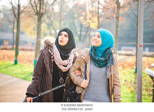 Two young women looking up whilst strolling in park