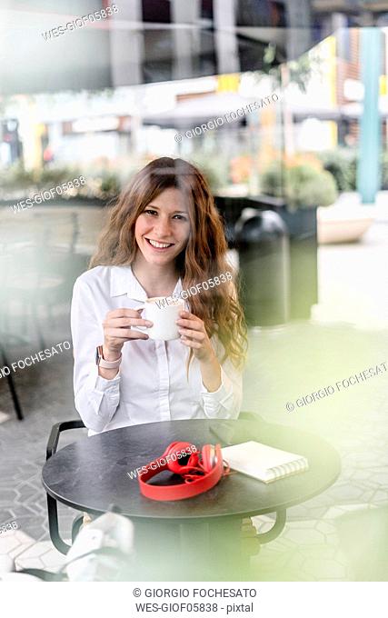 Young businesswoman sitting in cafe, working and drinking coffee