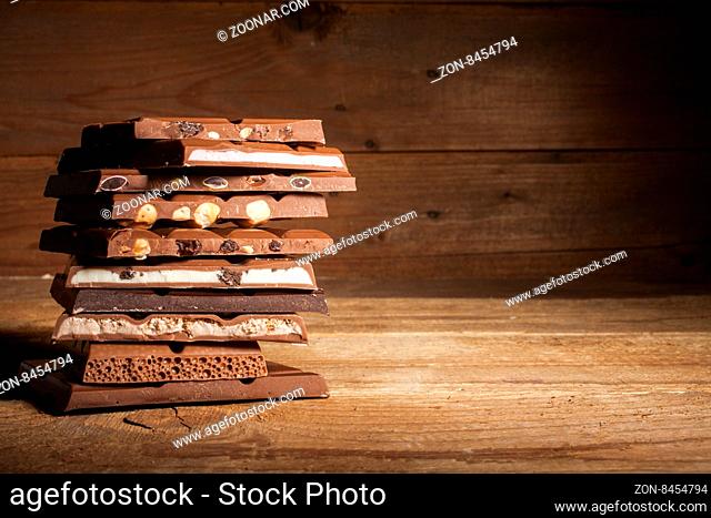 Chocolate blocks stack with different kind of chocolate on wooden background