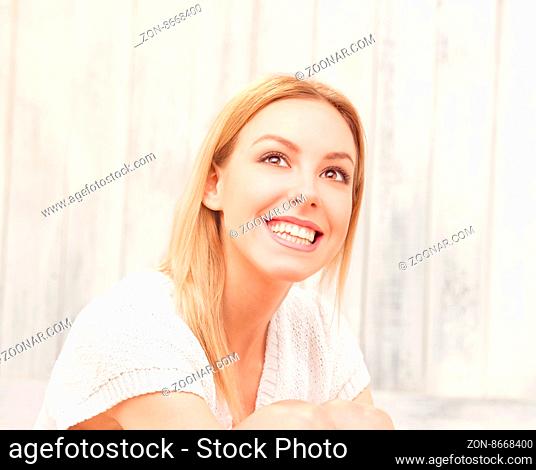 Portrait of beautiful blond lady looking away and smiling for the camera. Blonde posing in studio for photographer
