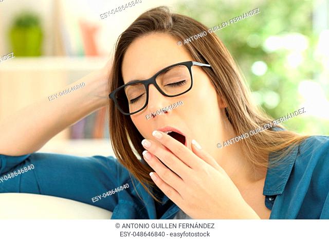 Fatigued woman yawning covering the mouth with a hand at home