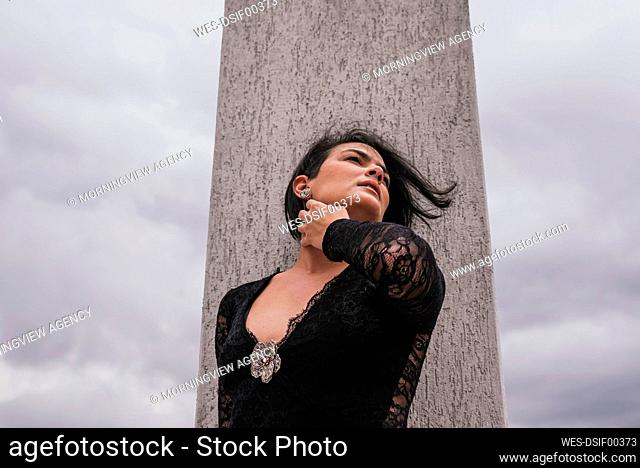 Thoughtful woman looking away while standing in front of architectural column