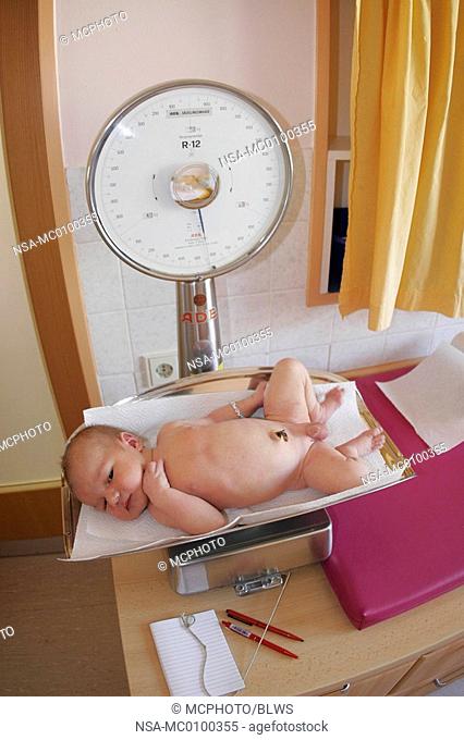 newborn baby on a weighing machine at hospital