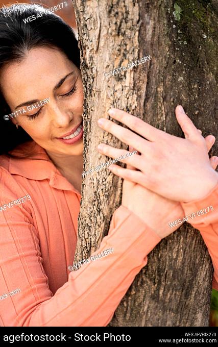 Affectionate woman embracing tree trunk in garden