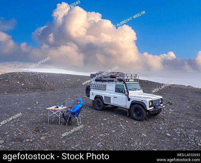 Man camping in front of off-road vehicle at coast of Myrdalsjokull icecap