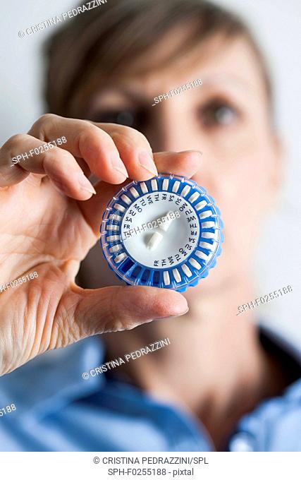 Woman holding hormone replacement therapy (HRT) pills. HRT pills are synthetic hormones used to treat menopausal women. They counteract the hormone deficiency...