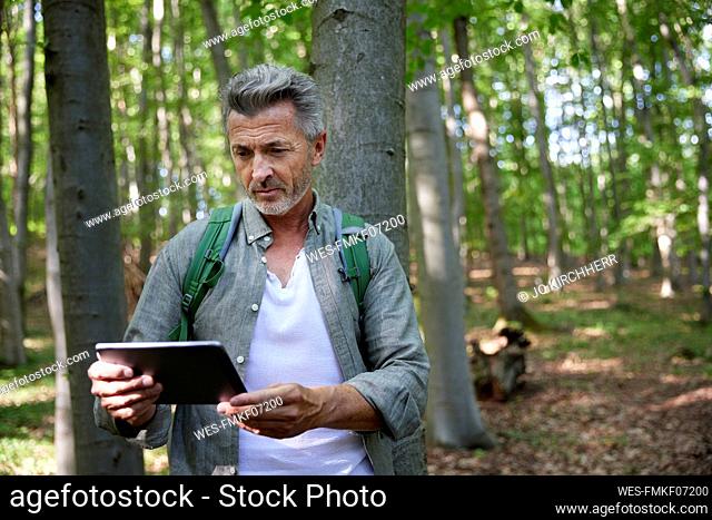 Man using digital tablet at forest